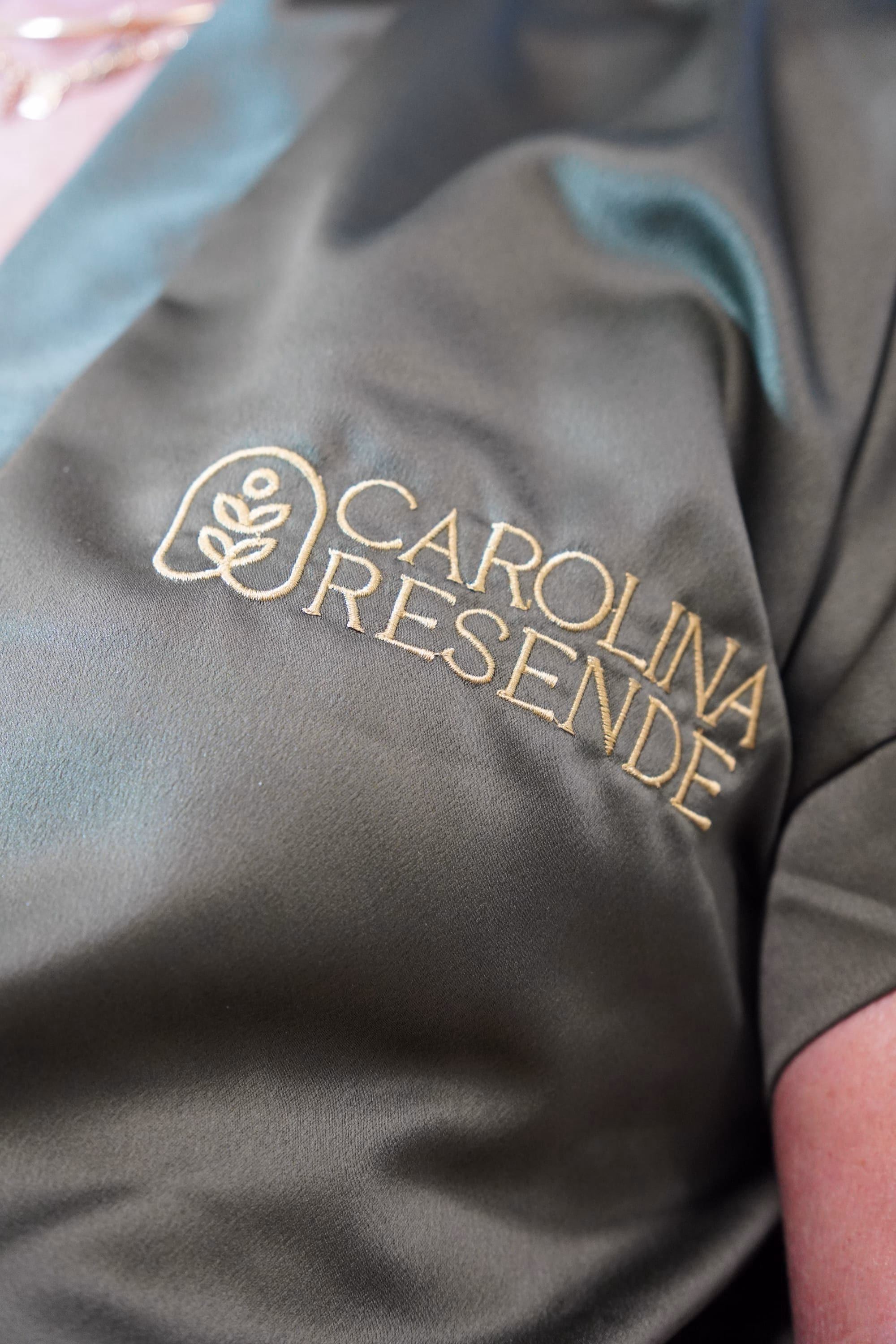 Detalhe do jaleco verde com a marca Carolina Resende bordada em dourado
